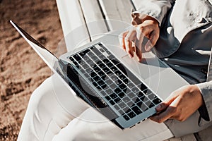 Girl writer sits on a park bench and works on a laptop