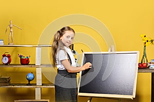 Girl writes on blank blackboard, copy space