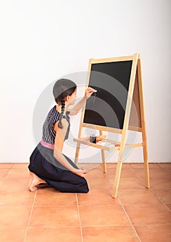 Girl writing on black blackboard - school education