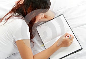 Girl writing book on the bed
