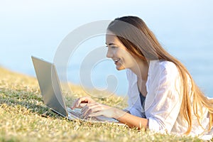Girl writing in a laptop on the grass