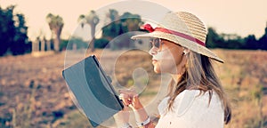 Girl writing on ltablet in countryside