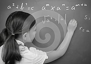 Girl writing math equations on blackboard
