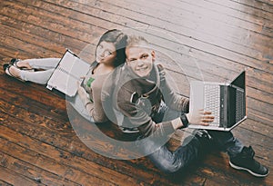 Girl writing in a notebook and boy with a laptop