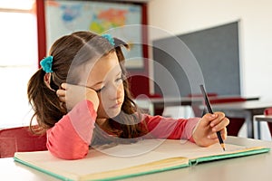 Girl writing on notebook in a classroom