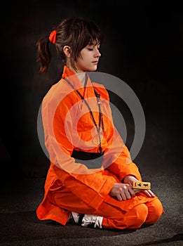 The girl wushu in orange costume to meditate