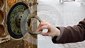 girl& x27;s hand holds an old round handle of a wooden door