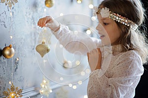 Girl of 8-9 years with delight admires gold Christmas-tree decorations.