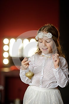 Girl of 8-9 years with delight admires gold Christmas-tree decorations.