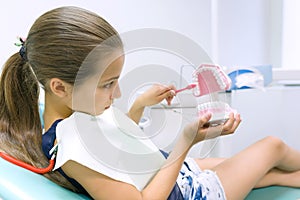 Girl 10 years old in dental chair, with tooth brush. Medicine, dentistry and healthcare concept
