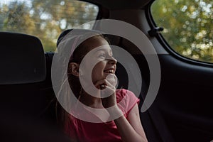 A girl of 8-10 years old rides in a car. Exploring nature, travel, family vacation. A girl of 9 years old rides in a car