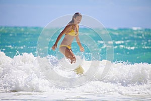 Girl in a yellow bikini surfing