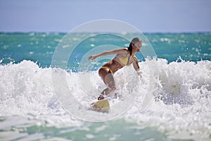 Girl in a yellow bikini surfing