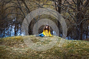 A girl in a yellow coat in the forest in early spring with a willow branch of twigs. A girl furing freshet or high water