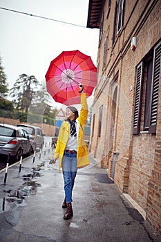 Girl in yellow coat and red umbrella walking  and enjoying on rainy day