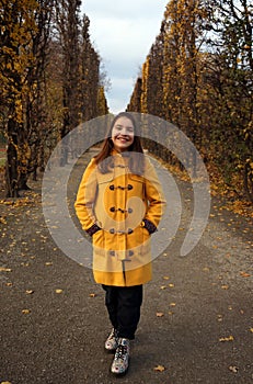 A girl in a yellow coat walks in the park autumn season Augarten