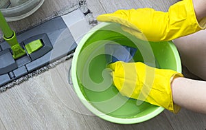 A girl in yellow gloves wets a rag in a bucket, cleaning equipment glove