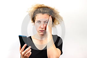 A girl with yellow hair is talking on a video link on a smartphone and with a serious thoughtful expression on her face