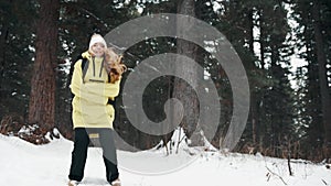 A girl in a yellow jacket jumps in the forest in winter to keep warm