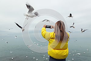 A girl in a yellow jacket, a view from the back, takes a photo on the phone outside the door.