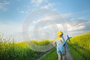 Girl in a yellow panama hat launches a toy plane into the field. Summer time, happy childhood, dreams and carelessness. Air tour photo