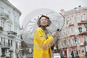 Girl in yellow raincoat with transparent umbrella