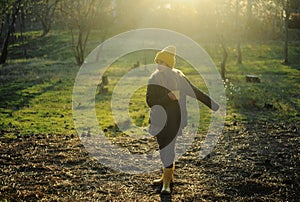 A girl in a yellow rubber boots walks through the forest. Travel concept with children. Autumn in the forest.