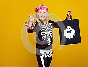 Girl on yellow showing shopping halloween bag and frightening