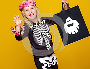 Girl on yellow showing shopping halloween bag and frightening