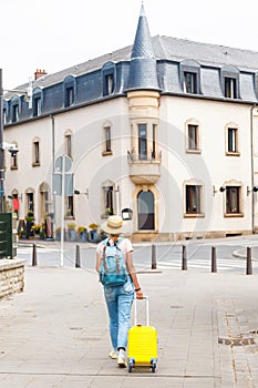 girl with a yellow suitcase heads to her hotel in the old European city