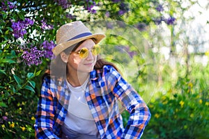 Girl in yellow sunglasses. Defocus beautiful young woman near blooming spring tree. Bush lilac flowers. Youth, love