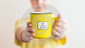 A girl with a yellow cup in her hand, on which was written Did you know photo