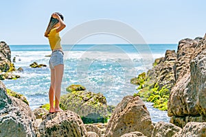 Girl in yellow top on coastal rocky seaside
