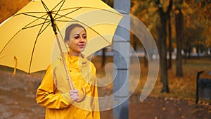 girl with yellow umbrella Slow motion rain city park. side view young woman hiding under umbrella from raindrop. walk