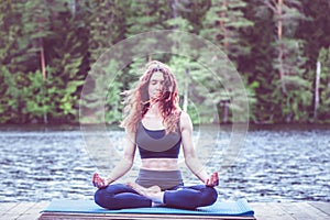 Girl in a yoga pose on the lake. Lotus position ,  Padmasana. The concept of appeasement,  healthy lifestyle