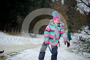 The girl of younger school age spends time in the winter park with pleasure.