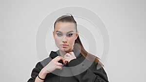 A girl in a youth modern black hoodie poses in a studio on a white background