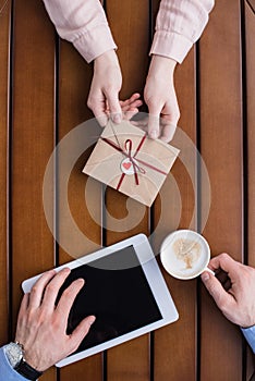 Girlfriend gifting postcard in envelope to boyfriend with tablet and coffee