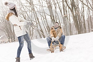 Girlfriend pulling boyfriend on a sleigh