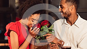 Girlfriend Receiving Bouquet Of Red Roses From Boyfriend In Restaurant