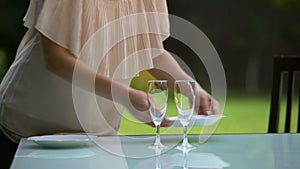 Girlfriend serving plates and wineglasses for date, family dinner outdoors