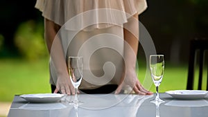 Girlfriend serving plates and wineglasses for date, family dinner outdoors