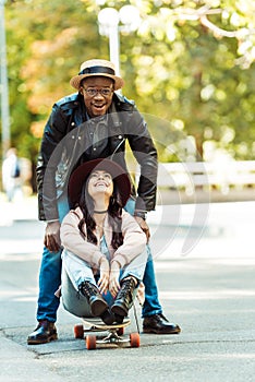 girlfriend sitting on a longboard and her boyfriend