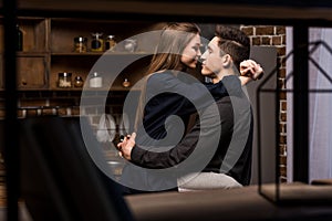 girlfriend sitting on table in kitchen and going to kiss boyfriend