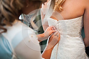 Girlfriend tying bride corset wedding dress white