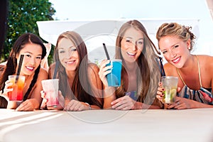 Girlfriends in beach bar drinking cocktails
