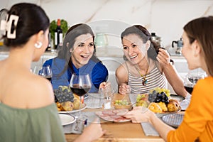 Girlfriends chatting and drinking wine in kitchen