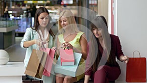 Girlfriends in colorful garments after shopping discuss their purchases together while sitting at mall during black