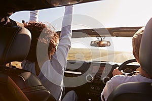 Girlfriends driving with sunroof open, rear passenger POV