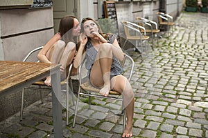 Girlfriends girls gossiping while sitting in a street cafe.